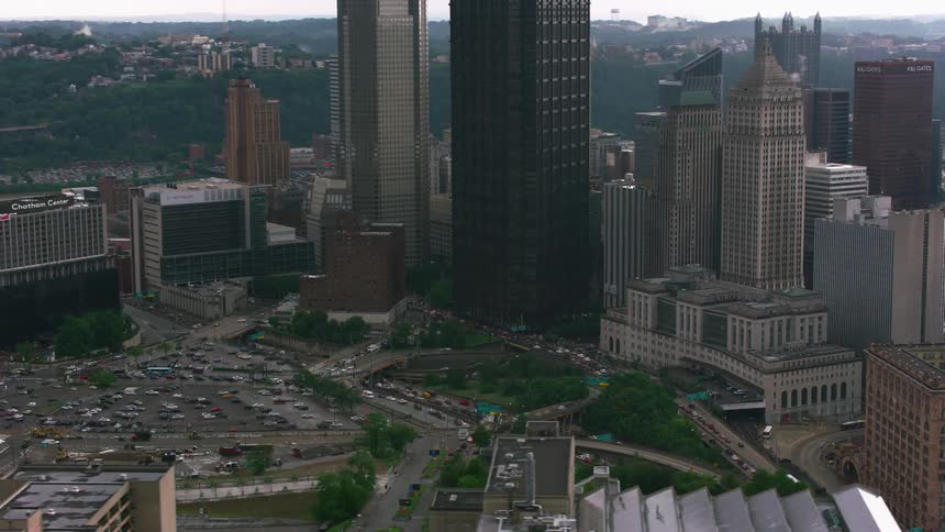 An aerial view of vehicles driving past high rise office buildings in a downtown area