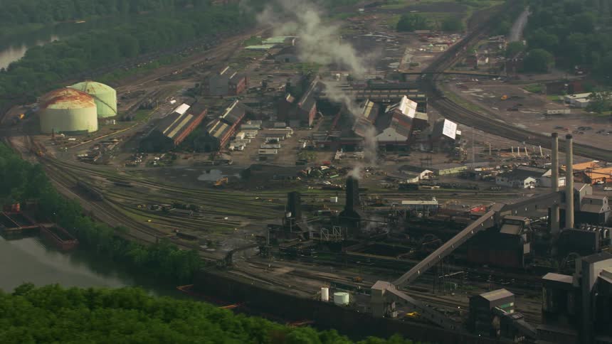 Smoke rises from a factory along a river