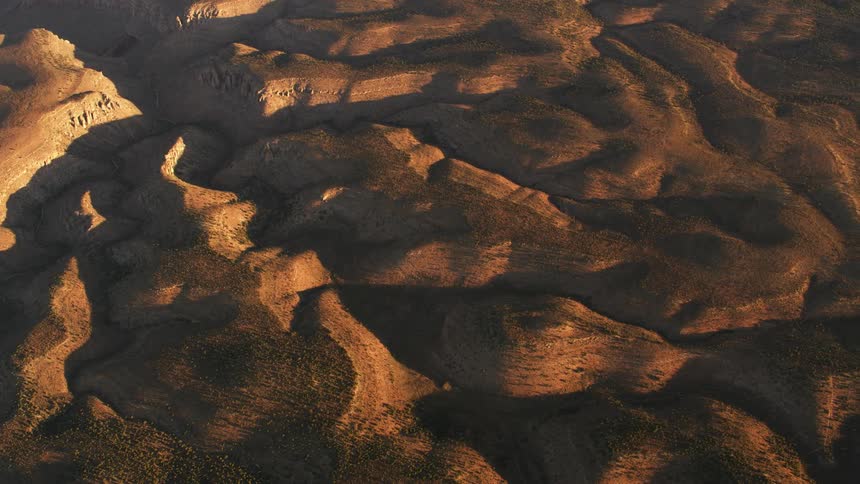 The sun shines upon desert badlands and mountains