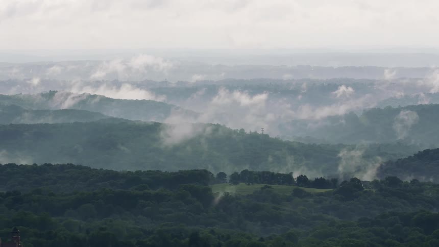 An aerial view of clouds moving over hills