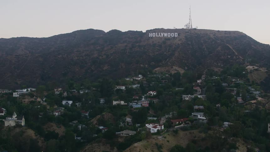 The hollywood sign sits on a mountain overlooking multiple neighborhoods