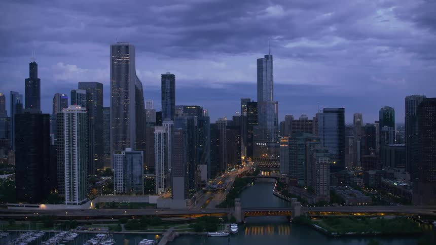 An aerial view of boats in the water in front of high rise office buildings in a city