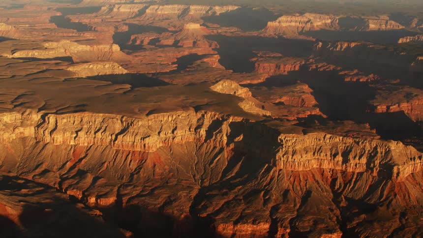 The sun shines on canyons and badlands showing layers of rock