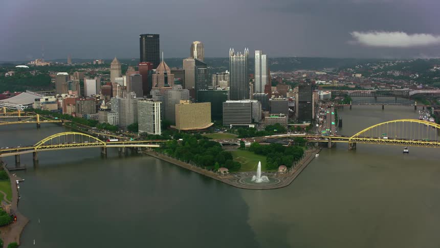 An aerial view of cars driving across bridges over a river and high rise office buildings in a downtown area