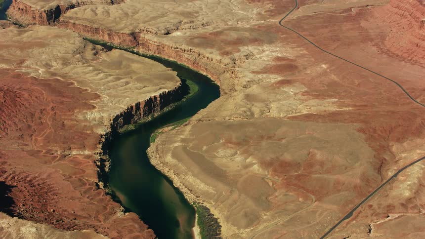 The sun shines upon a winding river canyon across the desert