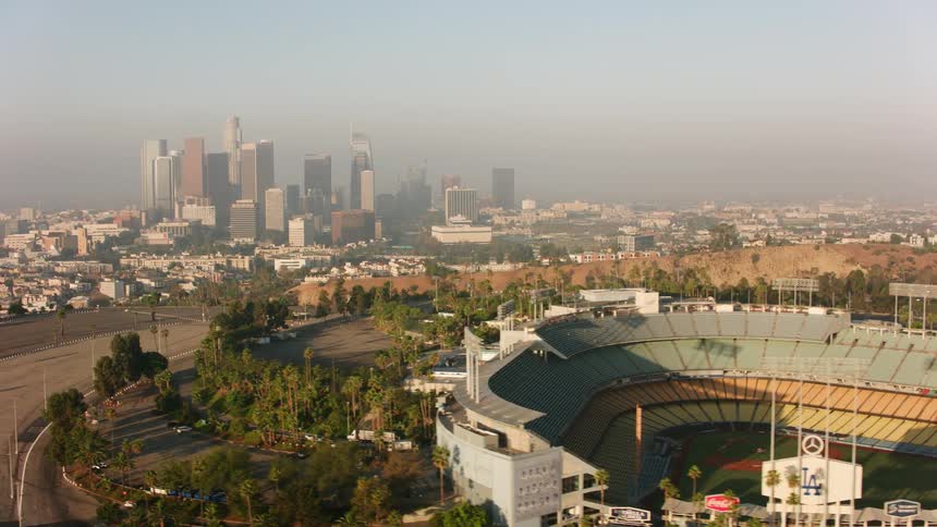 Traffic flows down controlled access highway between stadium on hill top and downtown