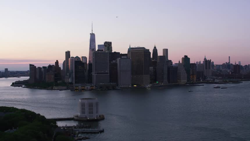 Boats sail in new york harbor and tall city buildings reach high in a clear sky