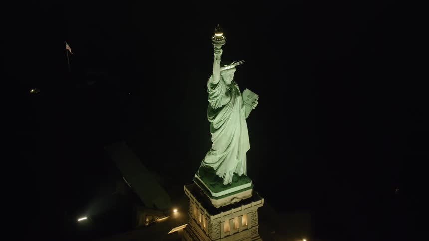 The statue of liberty glows bright in the night