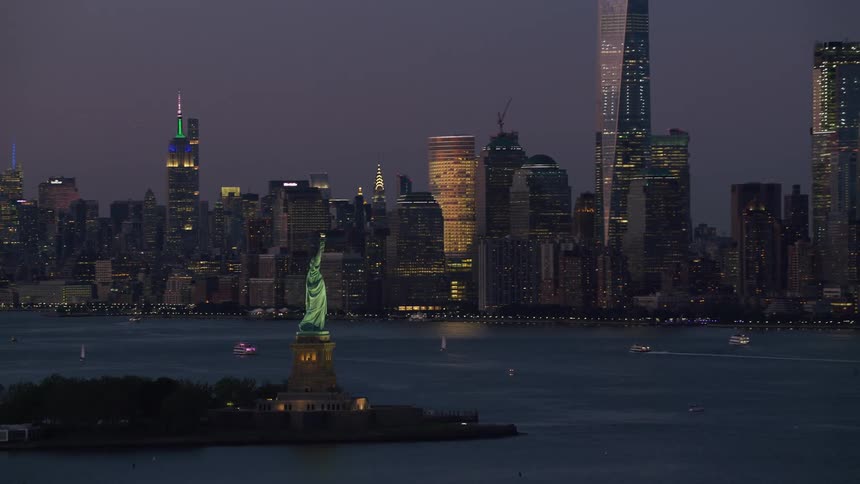 The statue of liberty shines against the new york skyline