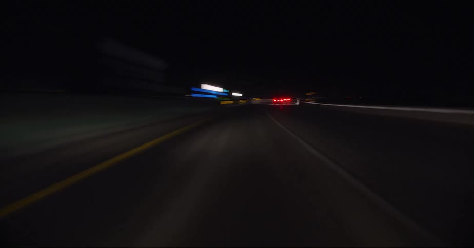 Headlights and tail lights shine as traffic moves on a highway at night
