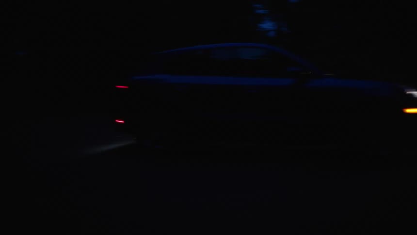 Headlights light up winding road as car drives along at night
