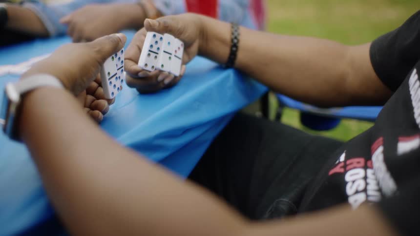 A man checks his dominoes during a game with friends outside