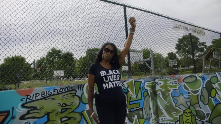 A woman is standing outdoors near a fence