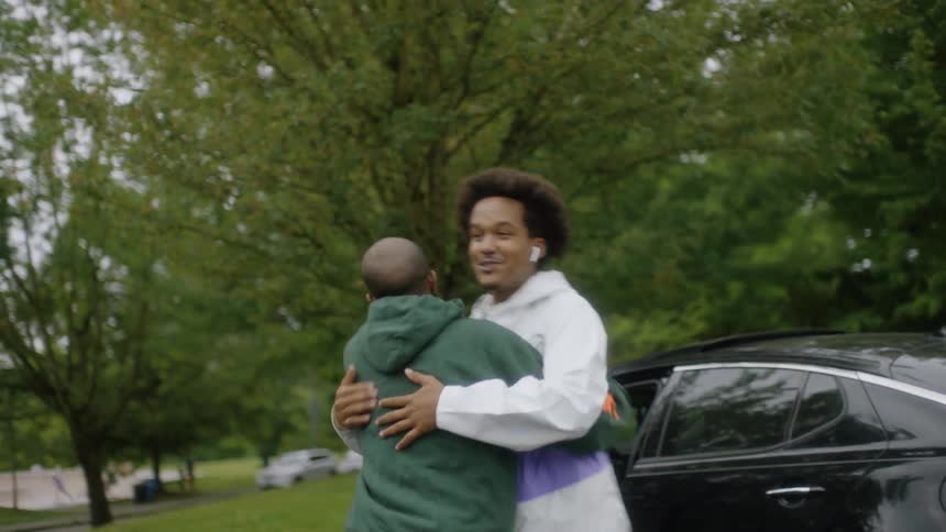 Family greets man who just arrived with smiles and hugs in park