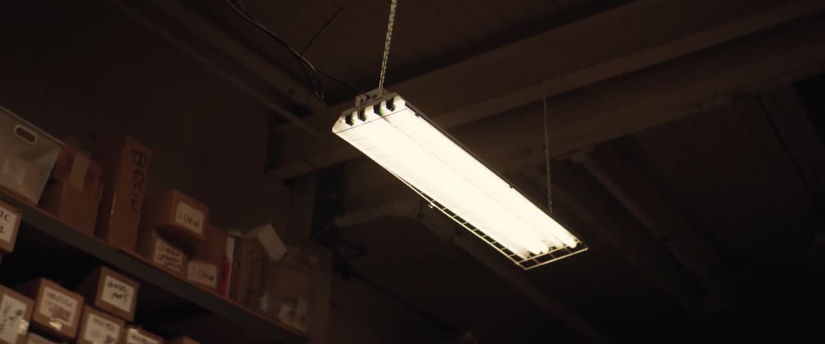 A light is hanging from the ceiling in a room with boxes on the shelves