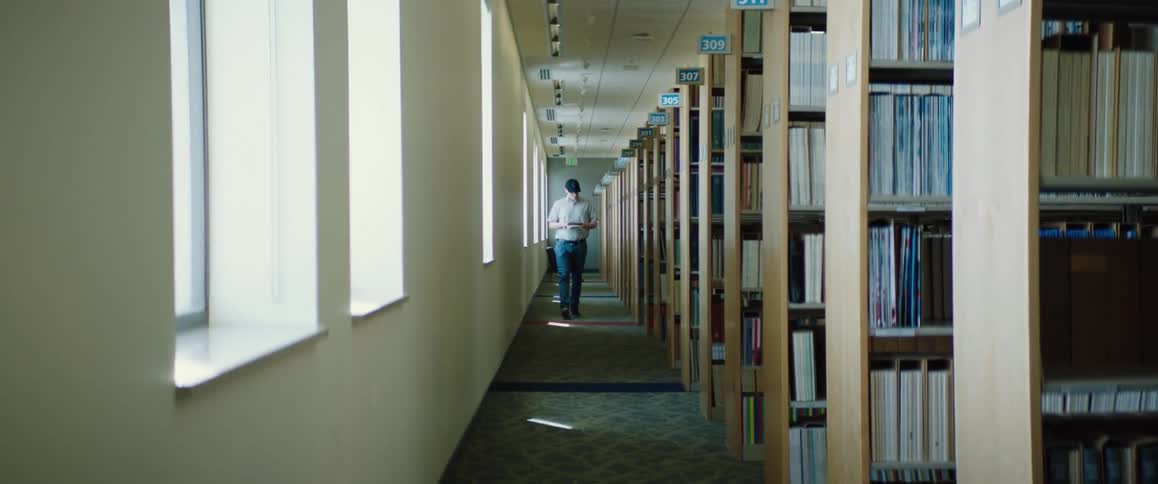 A man walks down an aisle of books at a library