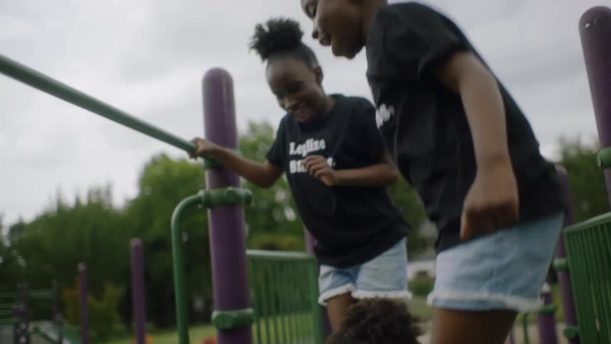 Girls with black t shirts shorts and white sneakers play in the playground on cloudy day