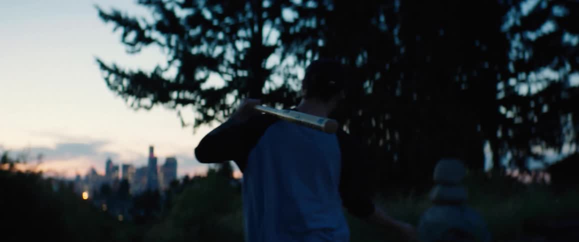Man with cap and white t shirt sways baseball bat walking