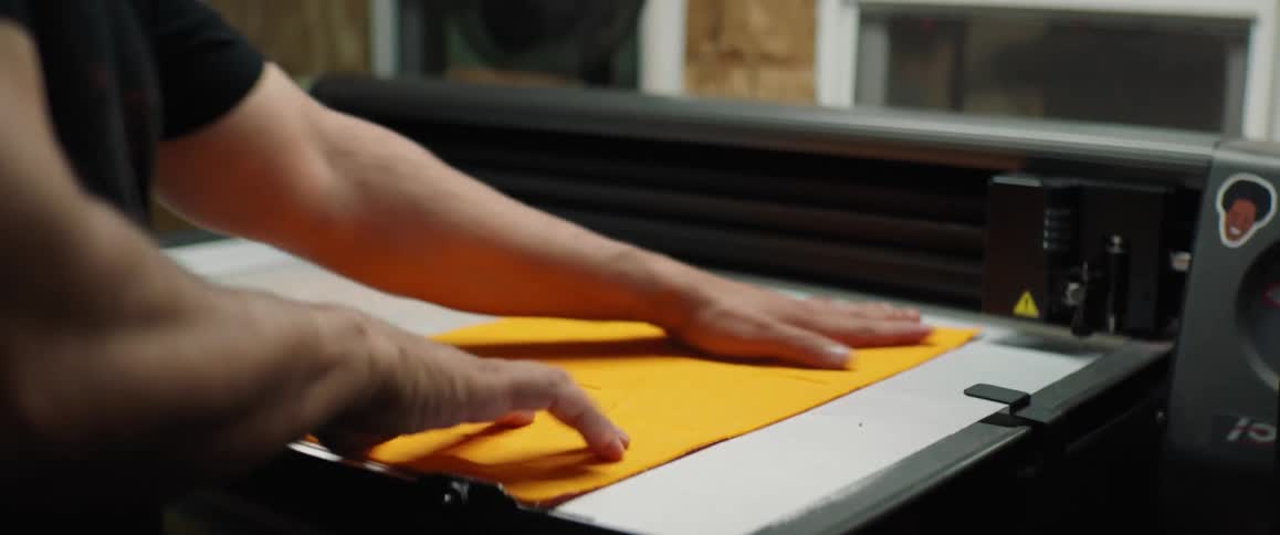 A man lays down felt on a large printer