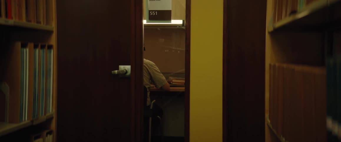 A person is sitting in at a table in a library