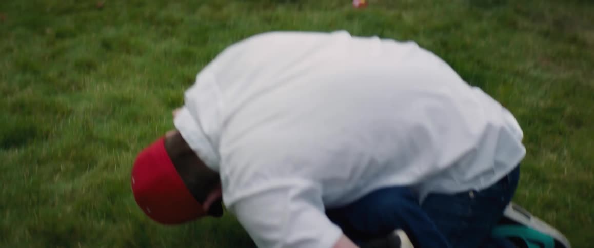 Dad kneeling on the grass holding his little boy making him laugh