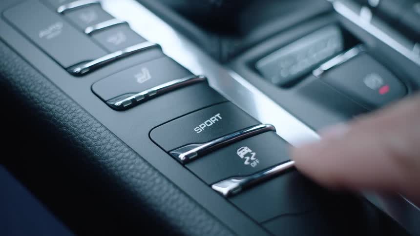 A driver puts his car in sport mode by pressing the button on the console