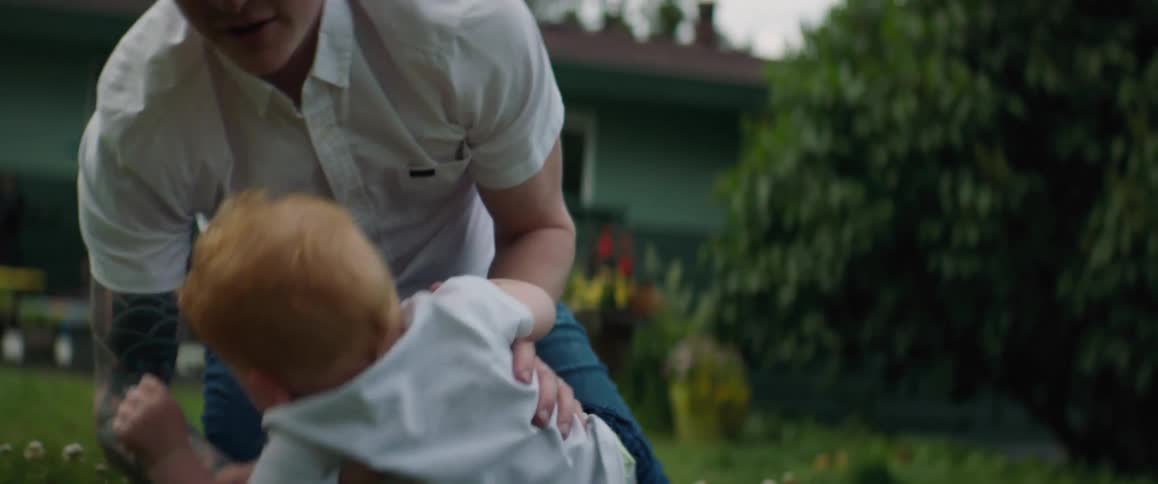 A dad playing with his son in the backyard throws him up in the air and catches him