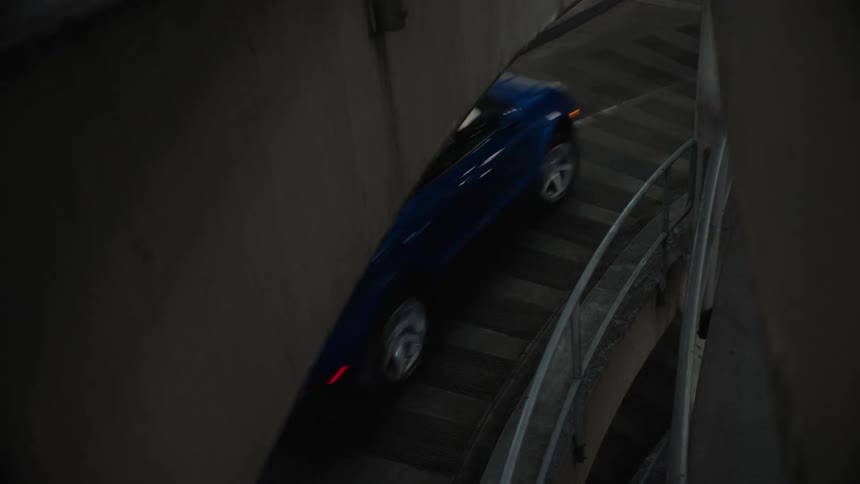 Car drives along ramp in parking garage