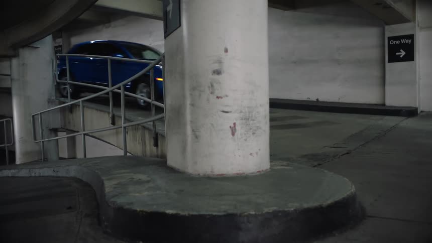Car drives down one way ramp between levels in parking garage