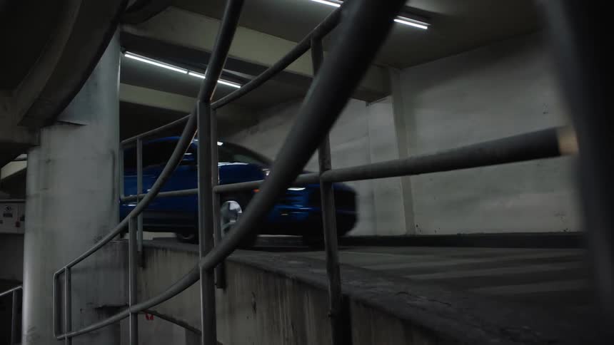 A car drives down a ramp in a parking garage