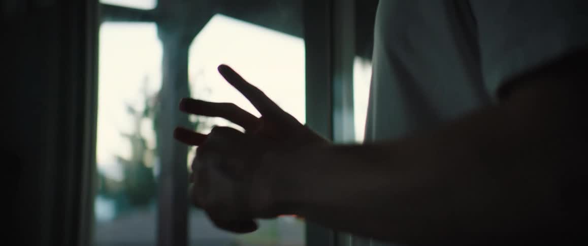 A man standing on his porch holding and squeezing a baseball in a frustrated manner