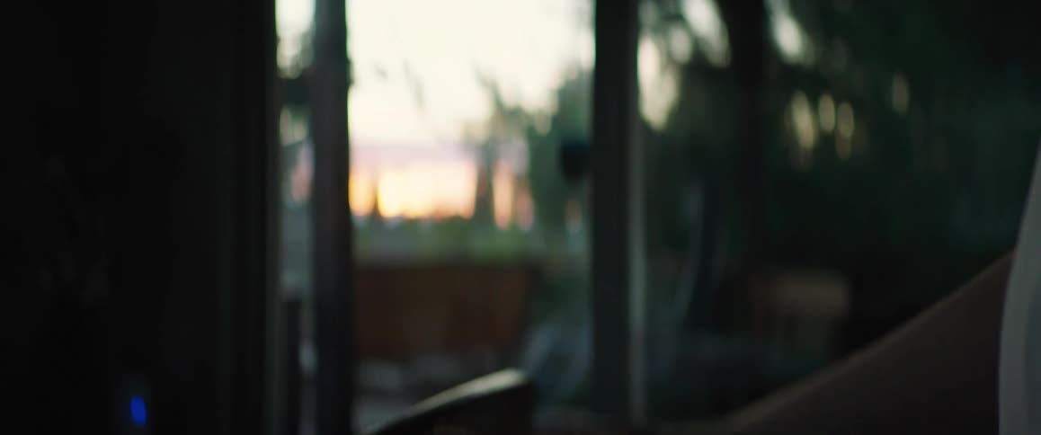 A man standing on a porch tosses a ball up and catches it with one hand then tosses it back and forth