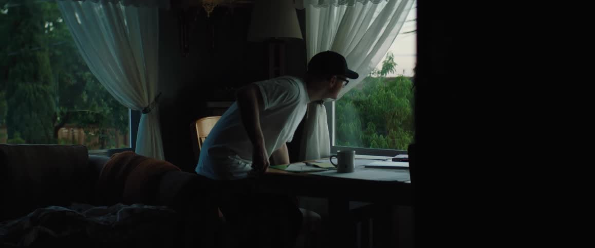 A man is in a restaurant and he sits down at a table near a big window