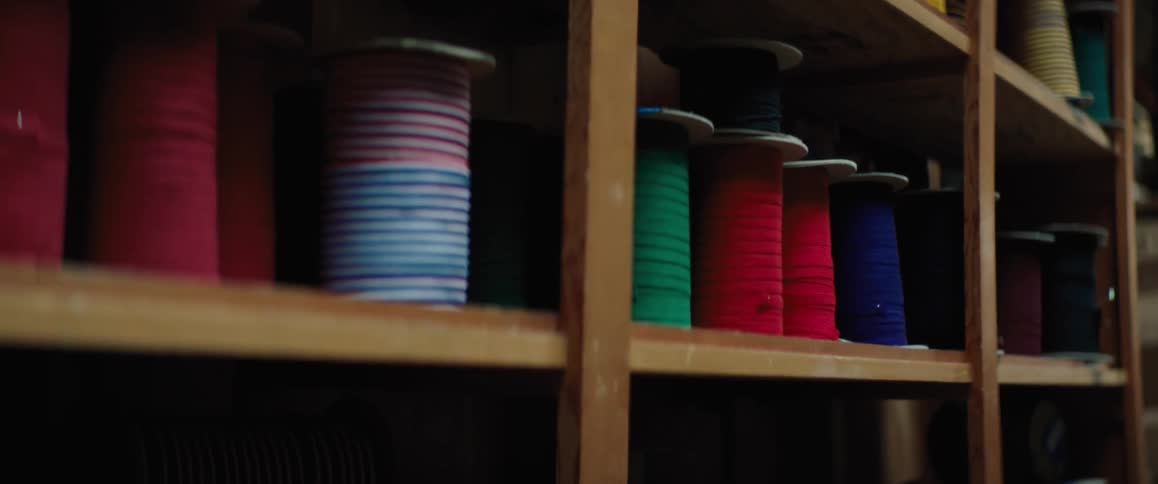 Spools of colored string are on a shelf in a room