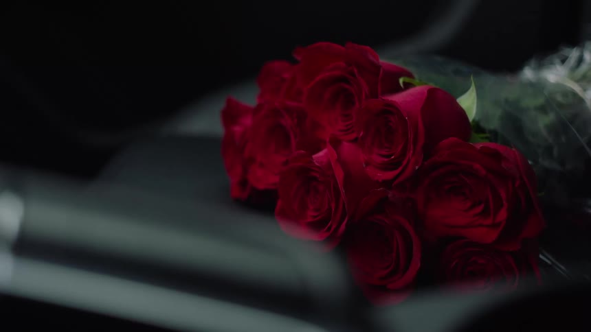 Bouquet of red roses sits on car seat n moving vehicle