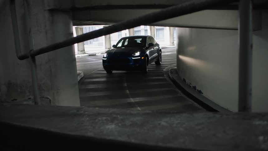 A car drives around a bend and pulls out of a parking garage