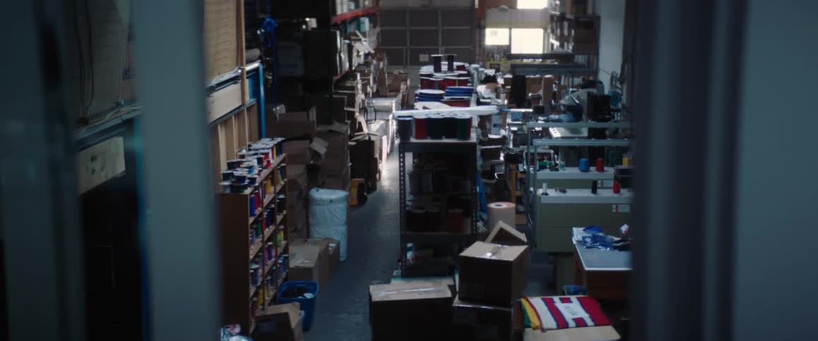 A woman walks around in a very messy storage area full of boxes and shelves with containers