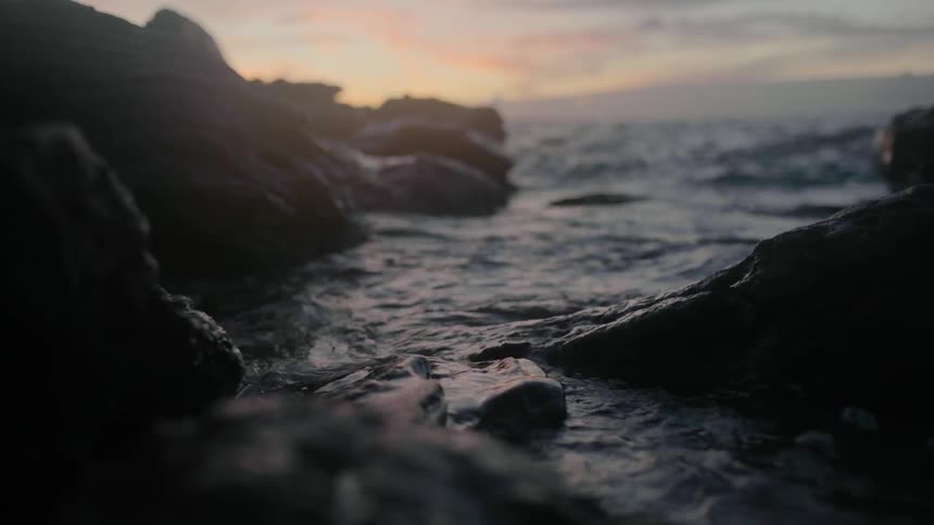 Water reflects the sunlight as waves roll into shore and splash against rocks