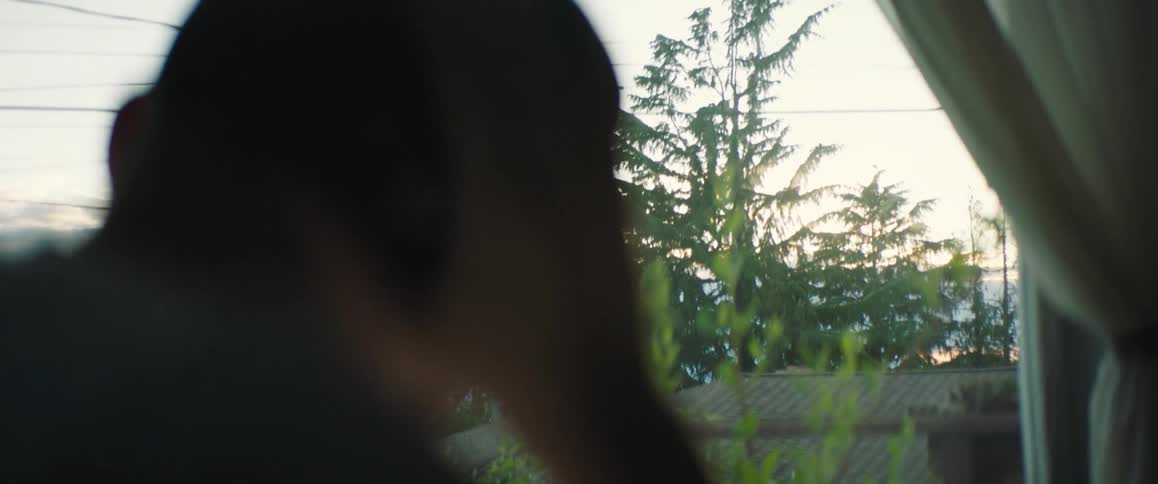 A man sitting at home at the window drinking coffee takes off his cap and hangs his head