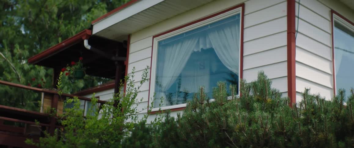 Someone inside a house is holding a numbered sports jersey in the window