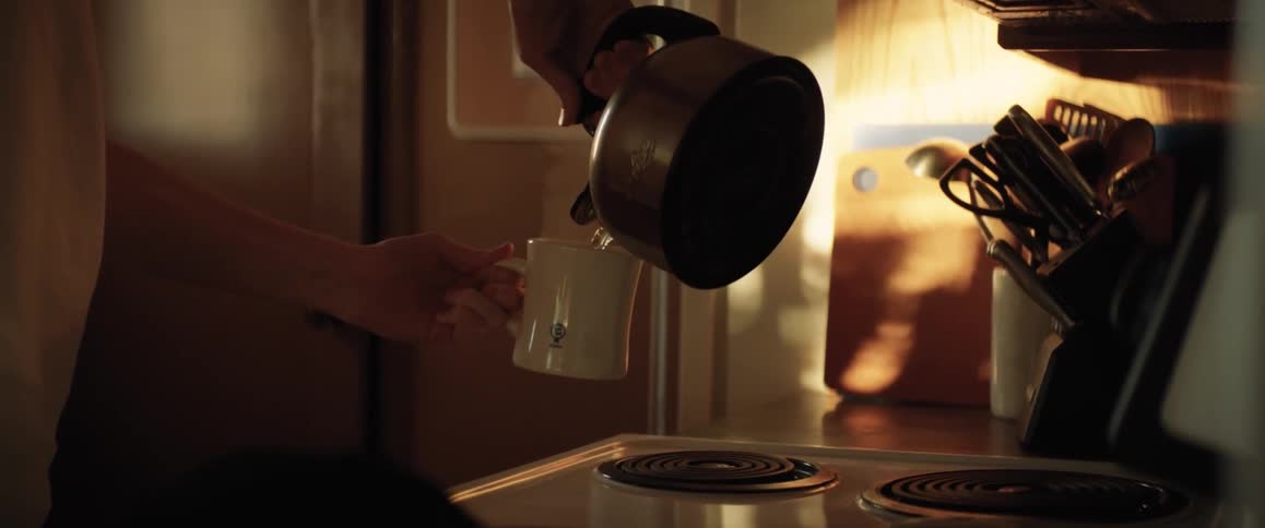 Man with white shirt pours hot water into white cup in the kitchen