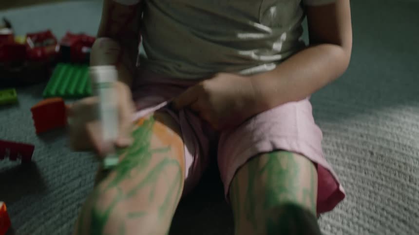 Kids sit on floor rug coloring their legs wit a marker having already colored their faces