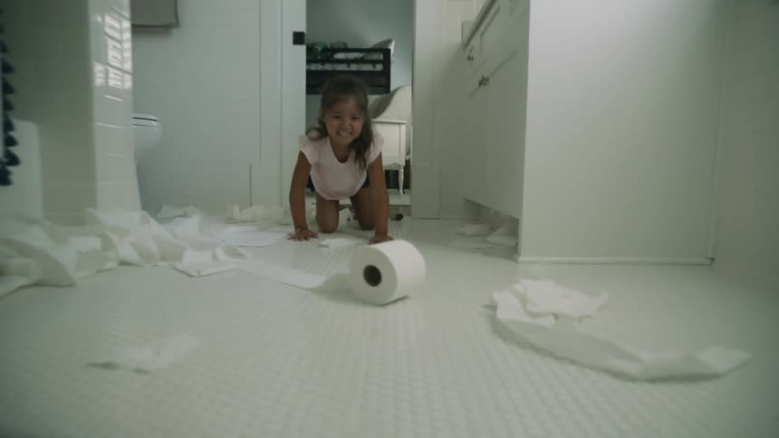 A child rolls toilet paper all over the bathroom