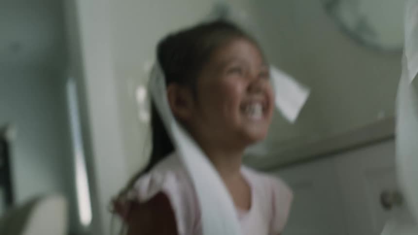 A little girl laughs as she bats away tissue paper tossed at her