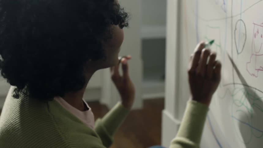 Mother talks to child while drawing with marker on home wall
