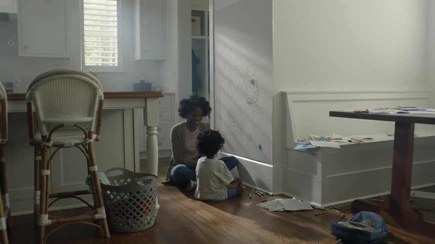 Mother hugs child as they draw on the wall with markers