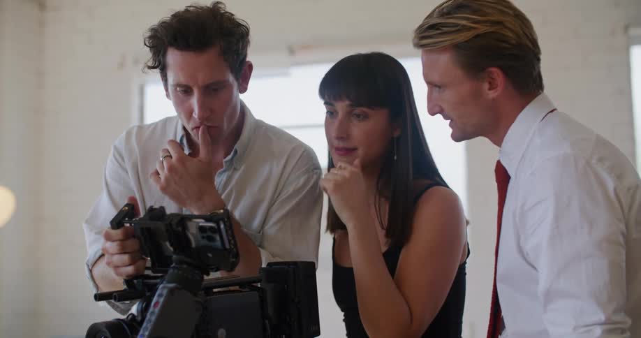 Director showing footage of a filmed scene to the actors inside a white room