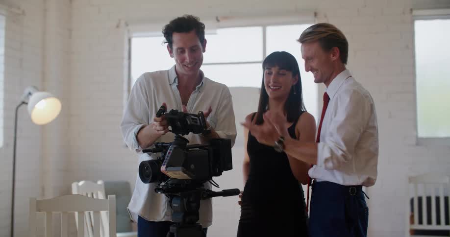 A group of filmmakers stand around and review footage on a screen