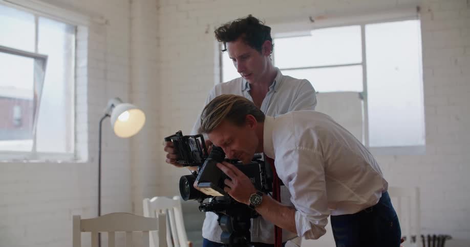 Director showing footage of a filmed scene to an actor inside a white room