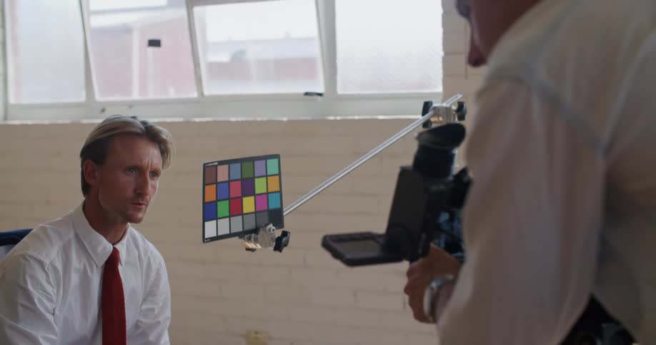 Man talks as he looks into film camera held by another man